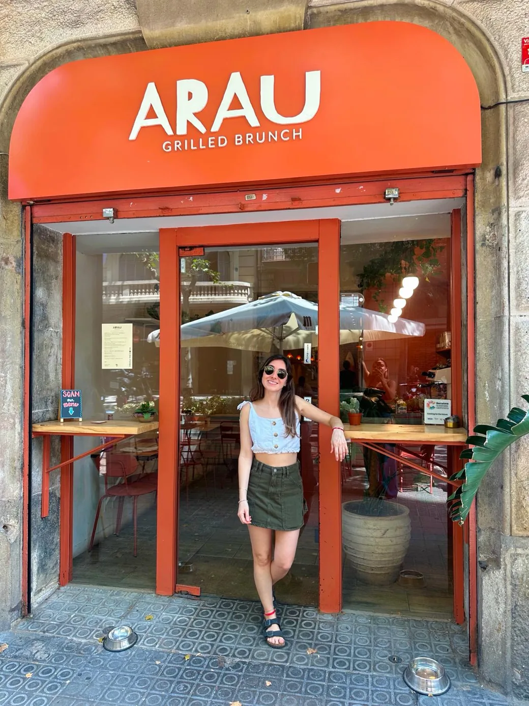 ARAU's facade at Carrer de Provença 322: terracotta awning with the «ARAU · Grilled Brunch» sign and Agustina, the founder, at the entrance