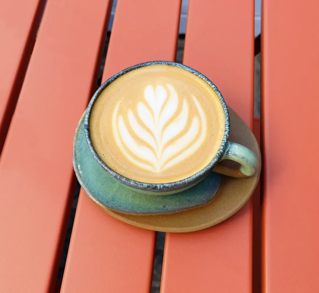 Flat white with latte art in a green ceramic cup